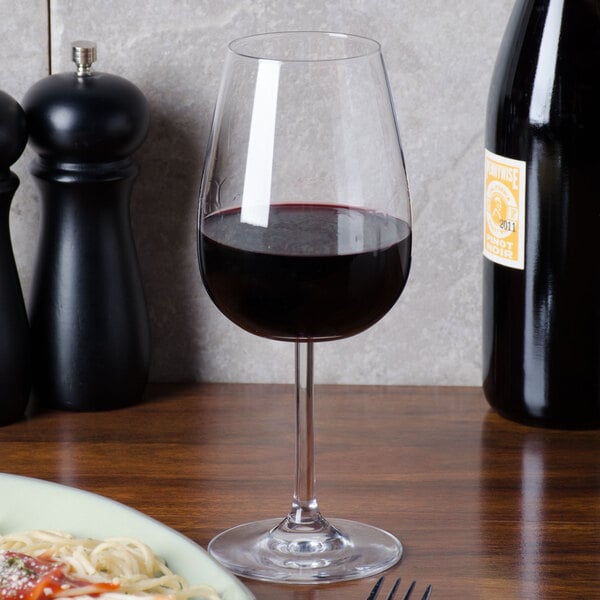 A Stolzle Vulcano wine glass filled with red wine on a table.