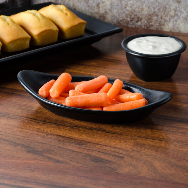 A black Hall China au gratin dish filled with baby carrots.