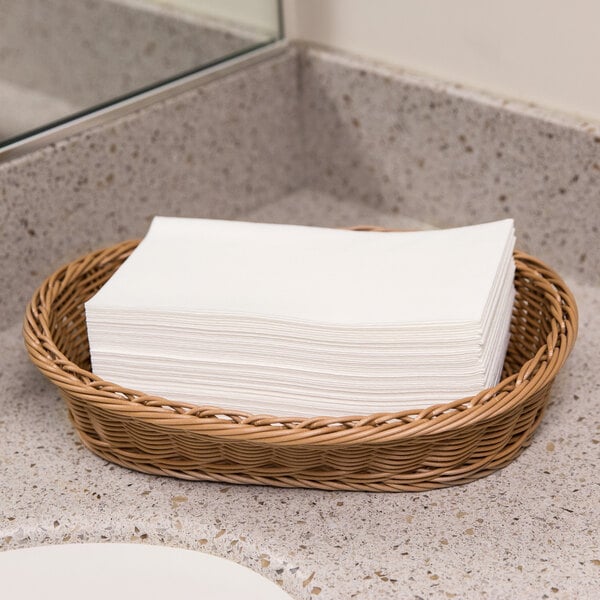 A basket of Lavex Linen-Feel white paper guest towels on a counter.