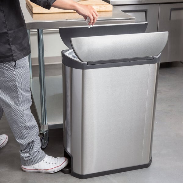 A man standing next to a Rubbermaid Slim Jim stainless steel trash can.