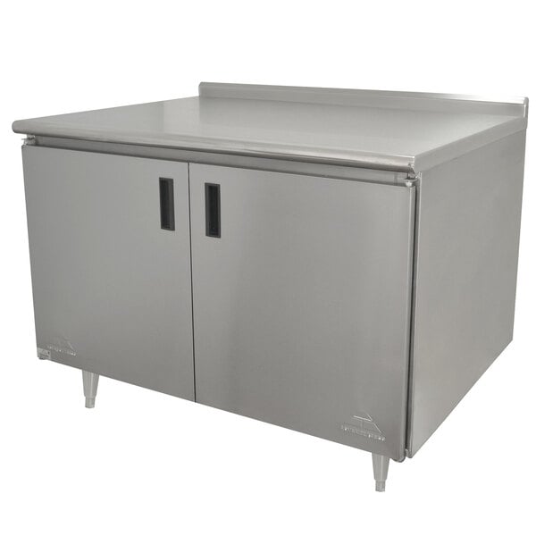 An Advance Tabco stainless steel enclosed base work table with hinged doors.