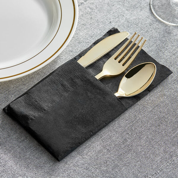 A black Choice ReadyNap dinner napkin with silverware in a pocket fold on a table.