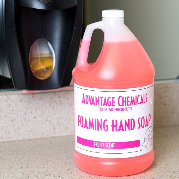 A pink bottle of Advantage Chemicals foaming hand soap on a counter next to a dispenser.