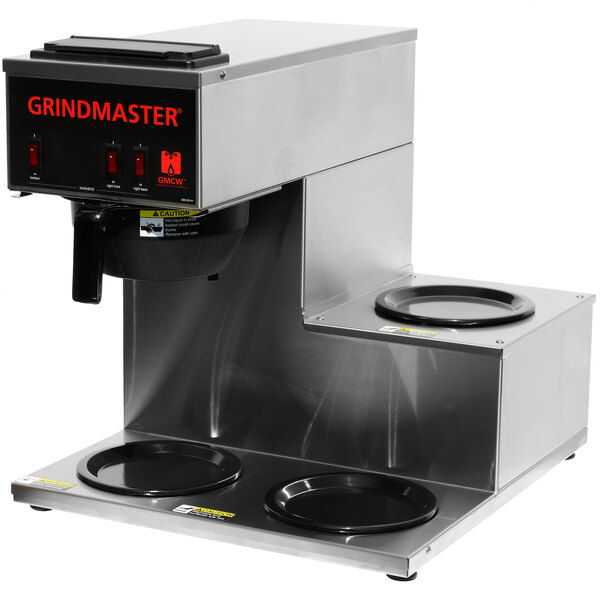 A Grindmaster coffee maker with three warmers on a counter in a professional kitchen.