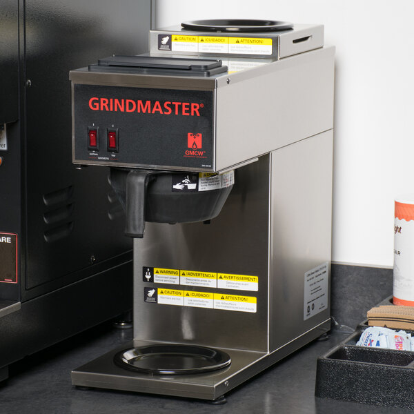 A Grindmaster portable pourover coffee maker on a counter with a coffee pot.