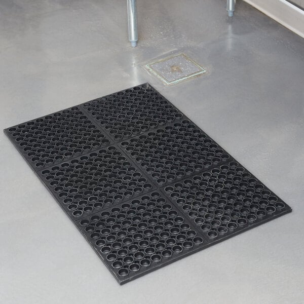 A black Cactus Mat rubber floor mat with holes in it.