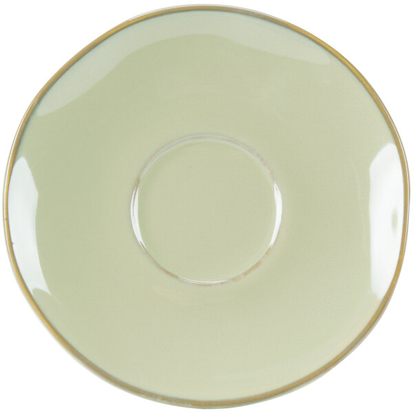 A white saucer with a gold rim on a green surface.
