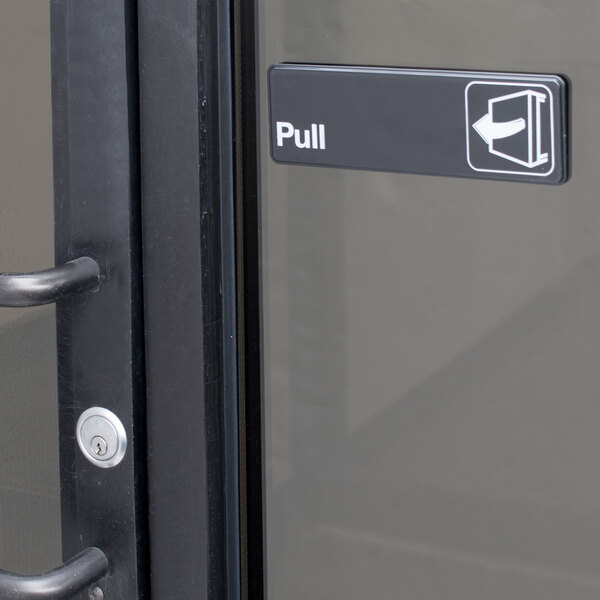 A black and white rectangular sign that says "Pull" on a door.