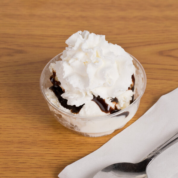 A Solo clear plastic sundae cup filled with ice cream, chocolate syrup, and a spoon.
