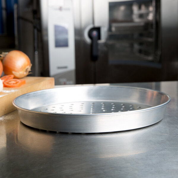 An American Metalcraft aluminum pizza pan with holes on a counter.
