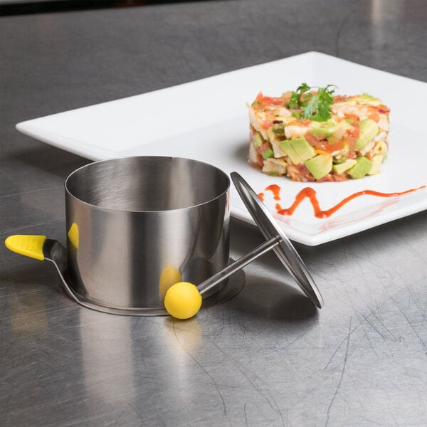 A silver plate with a metal container and food on it with Ateco stainless steel round molds.