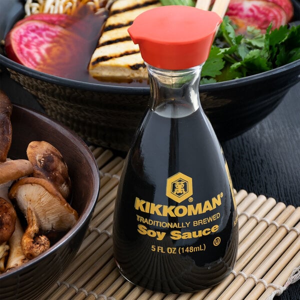 A bottle of Kikkoman Traditionally Brewed Soy Sauce next to a bowl of food.