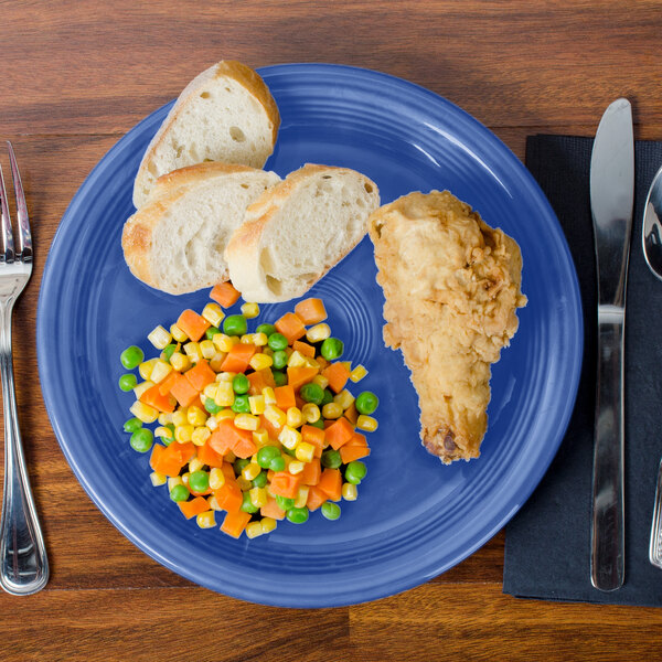 A Fiesta® Healthcare China plate with food, bread, and a fork and knife.
