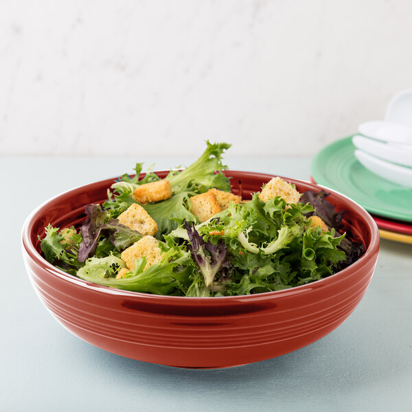 A red Fiesta China Bistro bowl filled with salad on a table.