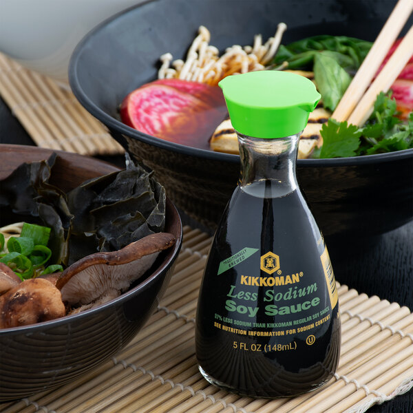 A bowl of noodles with a bottle of Kikkoman Less Sodium Soy Sauce on the counter.