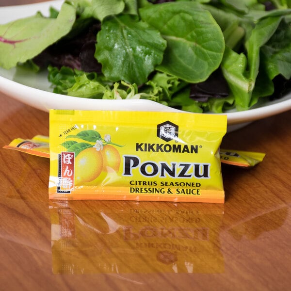 A bowl of salad with a Kikkoman Ponzu packet on the table.