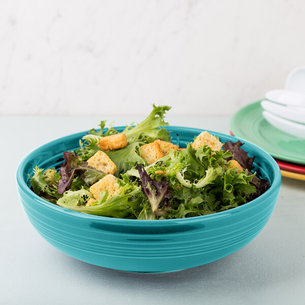 A Fiesta turquoise china bistro bowl filled with salad and a fork.