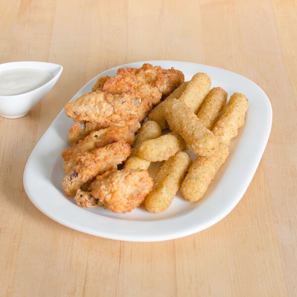 A Tuxton eggshell white china platter with fried chicken and cheese sticks and sauce.