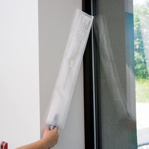 A person's arm with a Unger ProFlex Duster sleeve in a white plastic bag with a window.