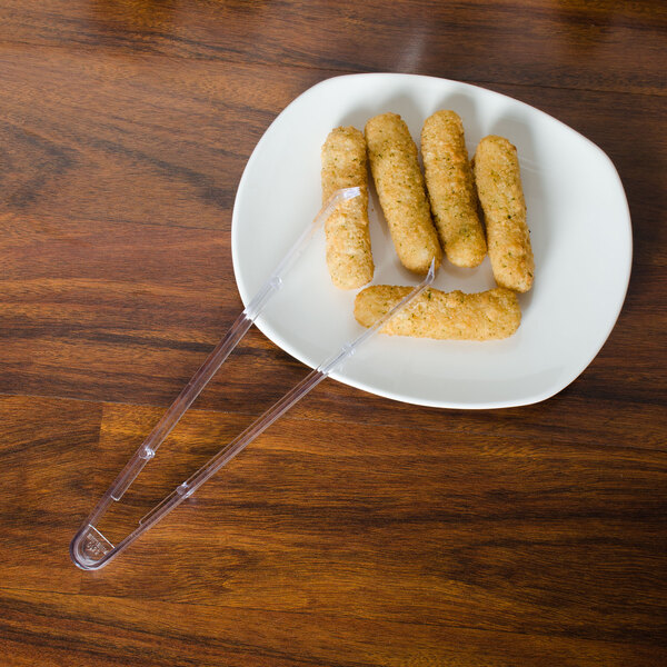 Clear plastic serving tongs on a plate of food.