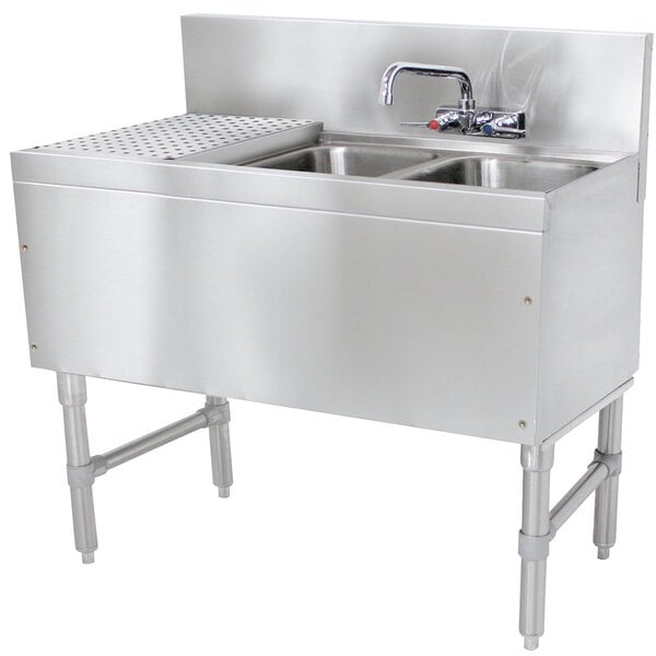A stainless steel Advance Tabco underbar sink with 2 bowls and a drainboard, with a splash mount faucet.