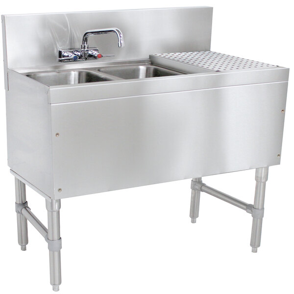 A stainless steel Advance Tabco underbar sink with two bowls, a drainboard, and a splash mount faucet.
