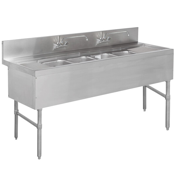 A stainless steel Advance Tabco underbar sink with 4 compartments, 2 drainboards, and 2 splash mount faucets.