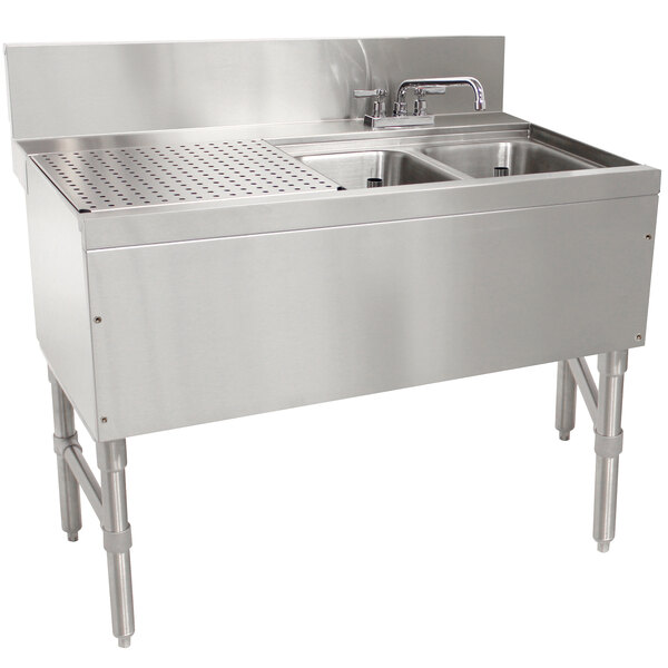 An Advance Tabco stainless steel underbar sink with 2 compartments, a drainboard, and a deck mount faucet.