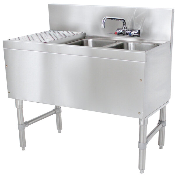 An Advance Tabco stainless steel underbar sink with 2 bowls, drainboard, and faucet.