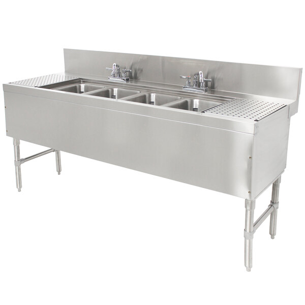 A stainless steel Advance Tabco underbar sink with four compartments and two drainboards on a counter.