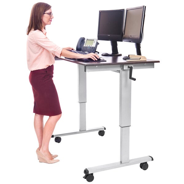 A woman standing at a Luxor stand up desk with a computer and phone.