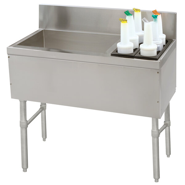 A stainless steel Advance Tabco ice bin with bottle storage and a cup on a counter.