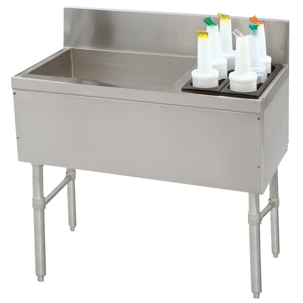 A stainless steel Advance Tabco ice bin and bottle storage unit with bottles on a counter.