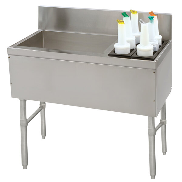 A stainless steel Advance Tabco ice bin with bottle holders on a counter.