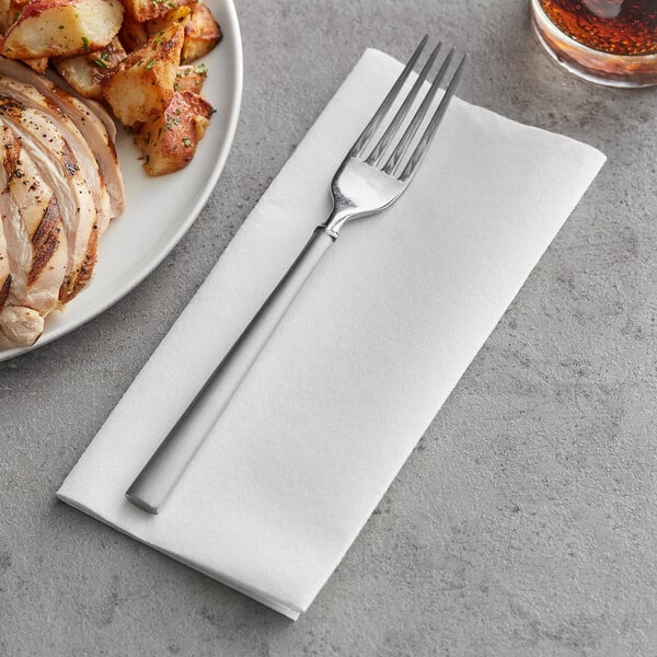 A Touchstone by Choice white linen-feel dinner napkin with a fork on top next to a plate of food.