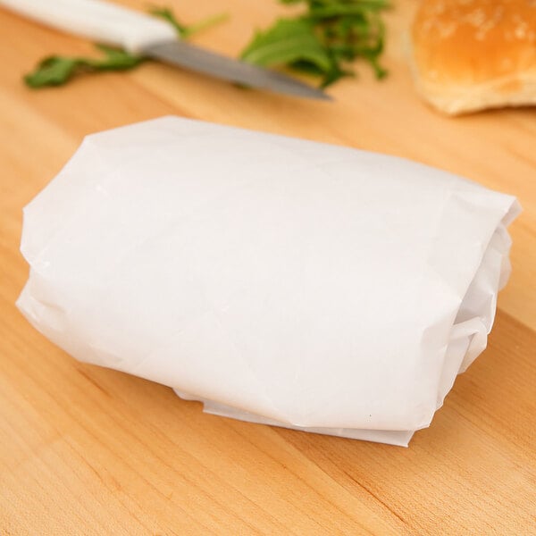 A roll of white Heavy Duty Dry Wax Paper on a table next to a knife.