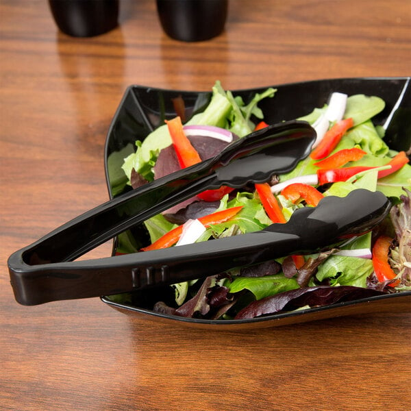 A salad with Fineline black tongs in a bowl.