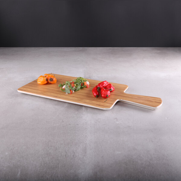 An Elite Global Solutions rectangular faux bamboo serving board with a handle with different vegetables on it.