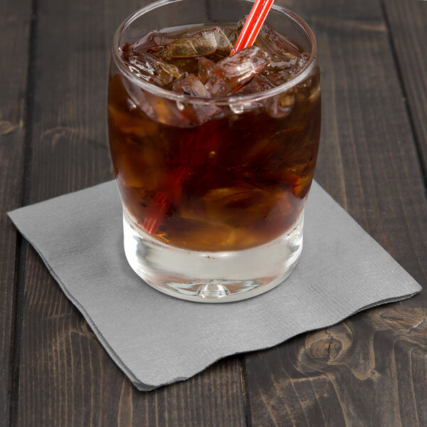 A glass of iced tea with a straw and a shimmering silver Creative Converting beverage napkin.
