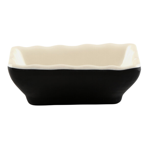 A black and white square sauce dish with a white rim.