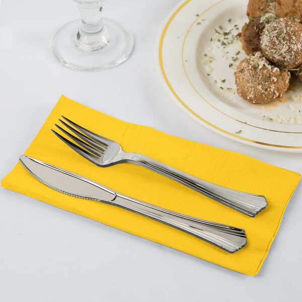 A knife and fork on a School Bus Yellow Creative Converting dinner napkin.