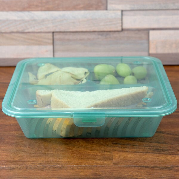 A GET jade plastic take out container with a sandwich and fruits inside.