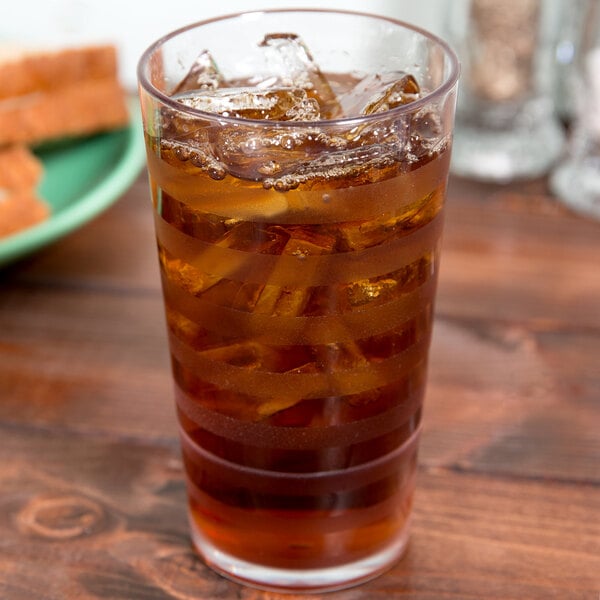 A close up of a GET Clear SAN Plastic Tumbler filled with ice tea and ice cubes.