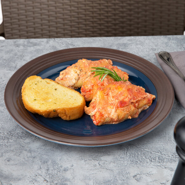 A close up of a Elite Global Solutions two-tone melamine plate with chicken and bread on it.