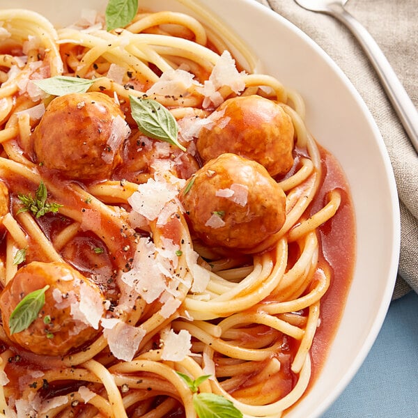 A plate of spaghetti and meatballs topped with tomato paste.