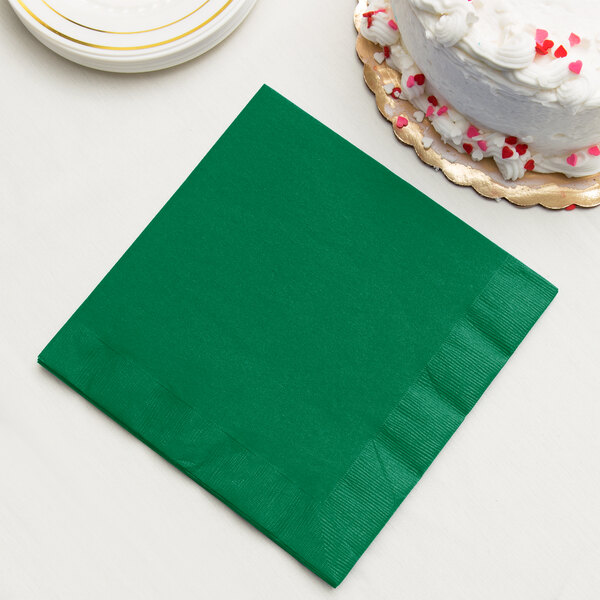 A Creative Converting emerald green paper napkin with a slice of cake on it.
