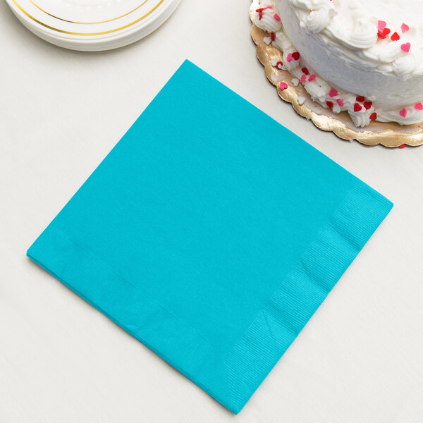 A Bermuda blue paper dinner napkin next to a white cake.