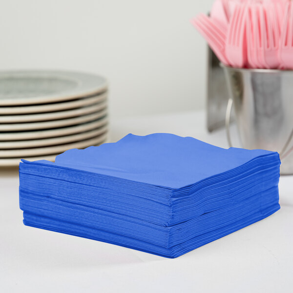 A stack of Creative Converting cobalt blue 1/4 fold luncheon napkins.