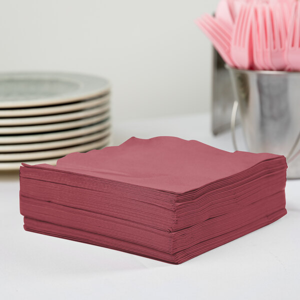 A stack of burgundy Creative Converting luncheon napkins on a table.