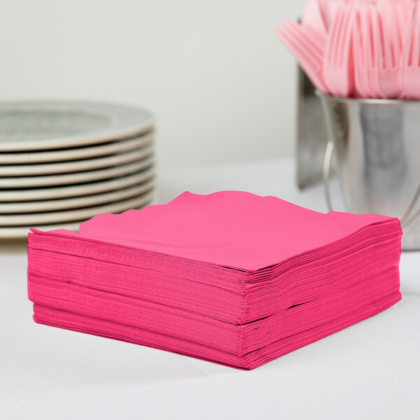 A stack of Creative Converting Hot Magenta Pink luncheon napkins on a table.